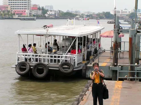 White cross-river passenger ferry moored at a Chao Phraya River pier in Bangkok