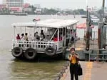 White cross-river passenger ferry moored at a Chao Phraya River pier in Bangkok