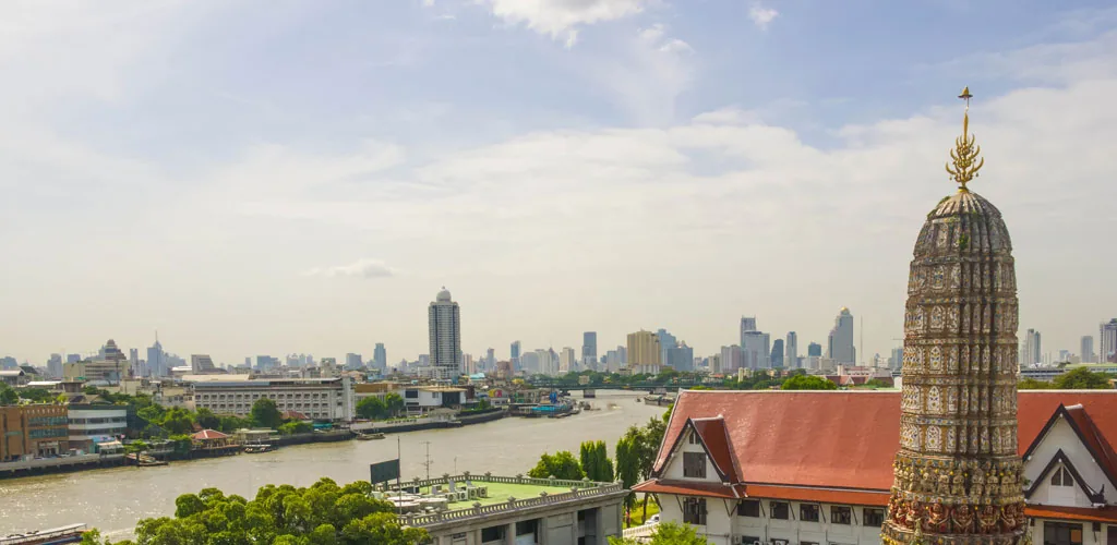 Wat Arun temple overlooking the Chao Phraya River and the Bangkok skyline